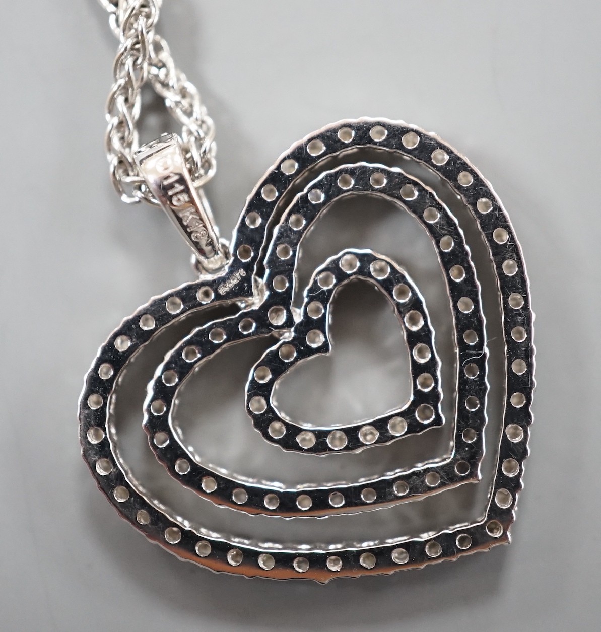 A modern 18k white metal and diamond set graduated concentric heart pendant, 27mm, on an 18ct white gold chain, 44cm, gross weight 11.3 grams
